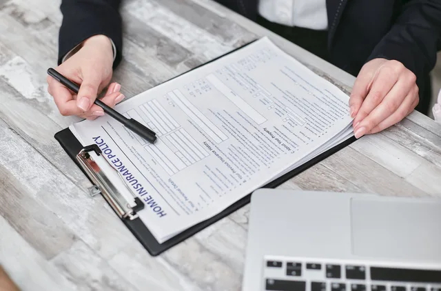 Close-up of hands reviewing a home insurance policy, emphasizing professionalism and finance. Checklist for judging umbrella coverage insurers before you bind