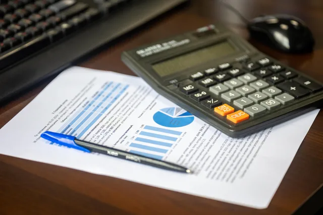 Desk with calculator, financial report, and pen, suggesting business analysis. What a cyber insurance calculator actually does with the numbers you enter