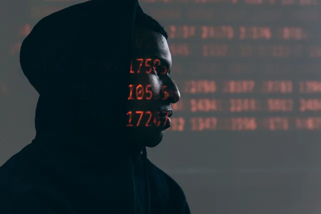 Side profile of a man in a hoodie, surrounded by red code, depicting cybersecurity theme. Cyber insurance examples with the reasoning laid bare
