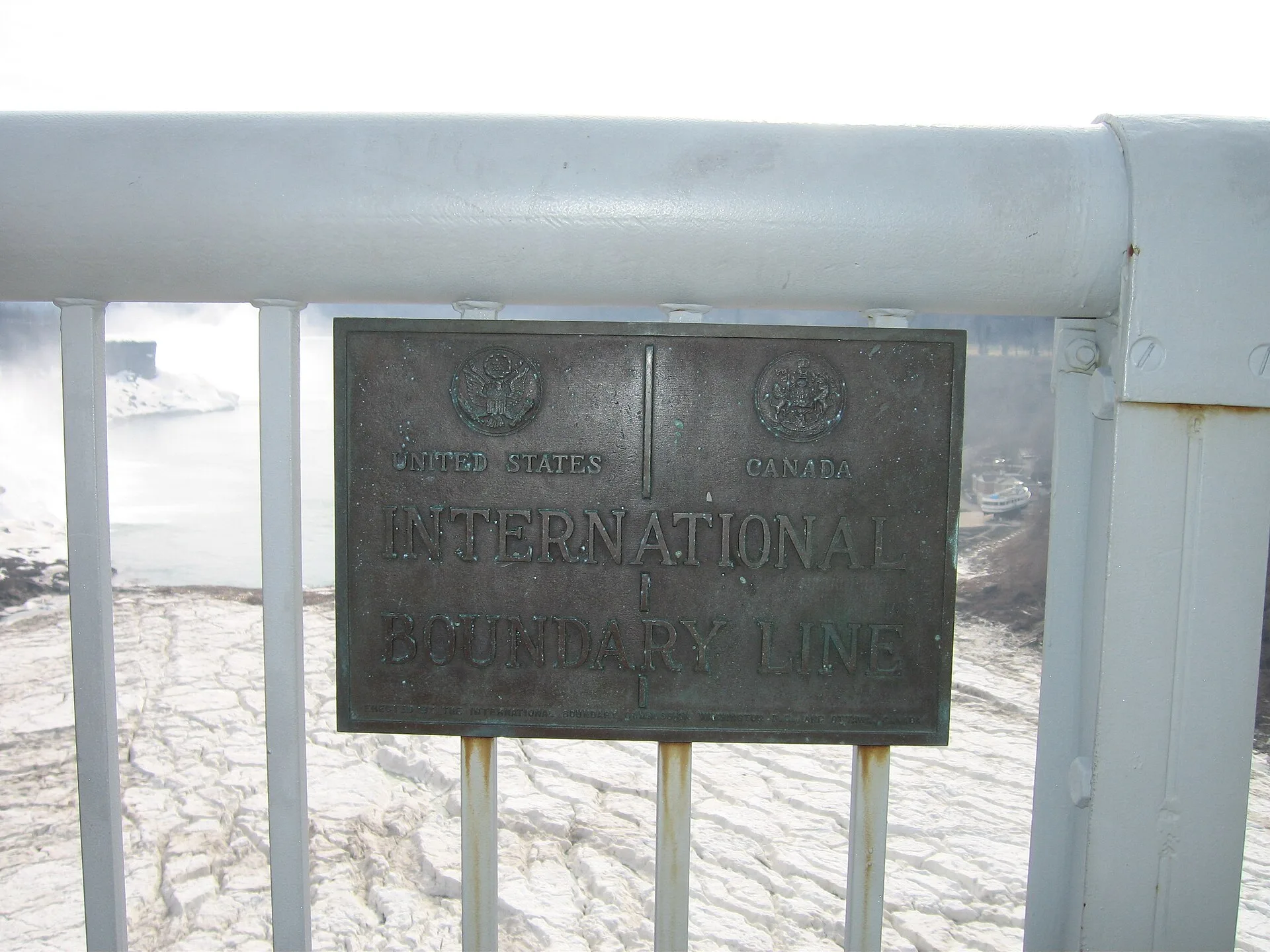 USA-Canada border sign at the Rainbow Bridge, Niagara Falls. Inscription: United States | Canada International Boundary Line / Erected by the International Boundary Commission Washington D.C., and Ottawa, Canada. Cyber insurance for US companies with Canadian staff: rating factors, quote ranges and privacy duties