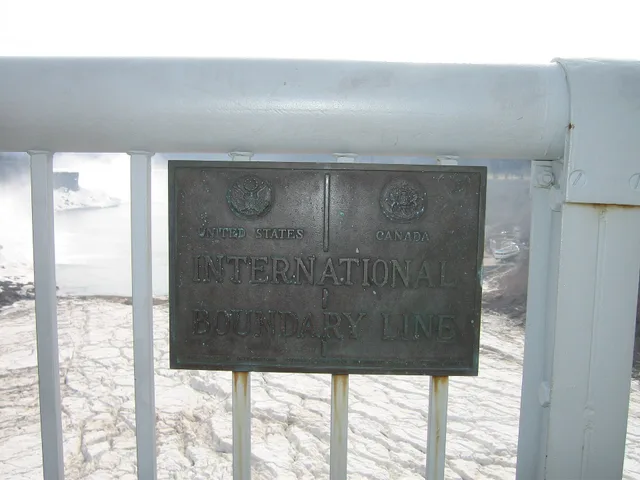 USA-Canada border sign at the Rainbow Bridge, Niagara Falls. Inscription: United States | Canada International Boundary Line / Erected by the International Boundary Commission Washington D.C., and Ottawa, Canada. Cyber insurance for US companies with Canadian staff: rating factors, quote ranges and privacy duties
